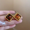 Primer plano de pendientes cuadrados dorados con textura de mármol ámbar en un dedo - 13# Pendientes de Botón de Plata - Dorado/Marrón - Cuadrado