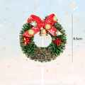 Detailed view of 6.5cm green Christmas wreath cake topper with red bow and gold bell - Snowflake Red Bow Pine Wreath Style