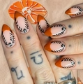 Detail von Halloween Stiletto Nägeln mit orangen French Tips und schwarzen Rankenmustern - Gelber Geleekleber + Nagelfeile
