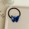 Detailed macro view of a jelly-textured blue butterfly hair tie on a ceramic tray - Dark Blue