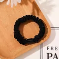 Detailed shot of black satin scrunchie with glossy buckle on light wood tray - Tencel Velvet Black
