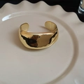 Brazalete geométrico irregular dorado pulido en una bandeja de cerámica blanca - Brazalete Dorado de Superficie Ancha