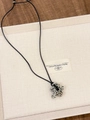 Detailed view of flower stone pendant on black cord over natural linen and wood background - Spotted Stone Flower (XL0588)