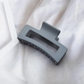 Elegant matte grey square hollow hair claw clip shown on a soft white fabric background - Gray