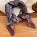 Dettaglio di una collana a sciarpa in seta vintage con motivi paisley su una scrivania in legno - Stile Fiore di Croce Caffè