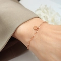 Elegante bracciale a catena in oro rosa con ciondolo a moneta lucida sul polso di una modella - Oro rosa / 15+5cm