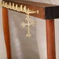 Dettaglio del ciondolo a croce dorata con zirconi su un supporto in legno naturale - Stile Croce 9