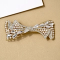 Elegant gold bow hair clip with embedded pearls and sparkling crystals on a beige surface - Qing Ni Ivory White