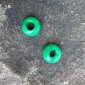 Two natural green stone rondelle beads with large holes on a rustic stone texture - Malay Jade