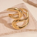 Primer plano de un brazalete dorado con líneas orgánicas sobre piedra con reflejos luz - Pulsera-Dorado Retorcido