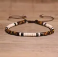 Adjustable woven bracelet with brown tiger eye stones and cream beads on a wooden desk - 102 Tiger Eye Pattern