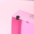 Detail of a matte black magnetic scarf clip showing strong suction on a box edge - Painted Gun Black