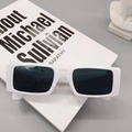 Vue détaillée de lunettes de soleil blanches rétro posées sur un livre d'art et une statue - Blanc Porcelaine