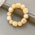Close-up of cream acrylic beaded bracelet with round and square beads on a grey book - White