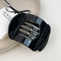 Macro shot of minimalist glossy black resin hair clip on a textured ceramic tray - L Black