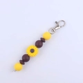 Macro shot of sunflower beaded keychain with yellow silicone beads and silver metal clasp - Coffee