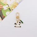 Dettaglio di portachiavi a panda in metallo con gancio dorato e ciondolo bambù - Panda seduto
