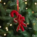 Red flocked candy cane Christmas ornament with a gold glitter bow on a tree branch - Red Flocked Candy Cane