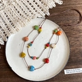Close-up of heart-shaped ceramic beads on a brown braided cord over a lace fabric - 37# Necklace-Brown-Multi (Ceramic Heart)