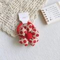 Detail view of red and beige polka dot floral fabric hair tie on a decorative desk - Red Polka Dot