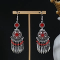 Close-up of bohemian tassel earrings with red beads on a golden display stand - E4726 Antique Silver Red
