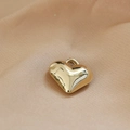 Dettaglio ravvicinato del ciondolo a cuore dorato su tessuto di seta beige liscio - Stile Cuore (10#)