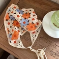 Detailed view of handmade crochet floral headscarf on a rustic wooden table setting - Blue and Orange Floral