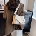 Stylish off-white textured bucket bag with wide strap, shown on a model's shoulder. - White