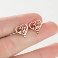 Macro shot of rose gold heart earrings with musical note cutouts held between fingers - Rose Gold