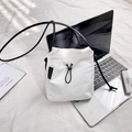 Detail of white nylon crossbody bag featuring a black drawstring closure and branded label - White