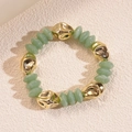 Dettaglio di un braccialetto in acrilico con metallo dorato e perle di resina verde - Bracciale-Verde Chiaro