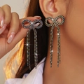 Black bow tassel earrings with sparkling rhinestones worn by a model in a close-up view - Stud Earrings / Black AB Color