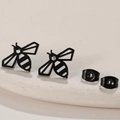 Minimalist black bee stud earrings with matte finish on a stone display plate - Black