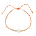 Detalle de una pulsera ajustable con una perla de agua dulce natural sobre un cordón naranja - Color Mezclado (QQ402A)