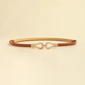 Detailed view of brown leather skinny belt featuring golden geometric twisted buckle - Camel