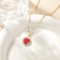 Macro shot of gold heart pendant necklace with red zircon stone on white ceramic - October - Red