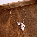 Detail of luxury beaded necklace with bear motifs and engraved silver bar on dark wood - Necklace / Silver-White