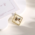 Rhombic gold pendant with blue dried flowers in white resin on a clean background - Rhombus Blue Brown Pressed Flower