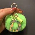 Close-up of green pompom keychain with resin letter D and colorful heart sequins - Letter D