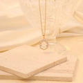 Detail of gold oval pendant with small diamonds on beige silk and stone textures - White