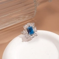 Macro detail of silver ring with deep blue rectangular stone and zircon halo - Blue Square Vintage Style