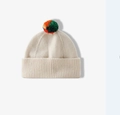 Détail du bonnet en tricot beige avec pompon coloré et bordure à revers côtelée - Taille unique / Blanc Cassé