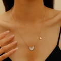 Detail of a gold heart pendant necklace with white enamel on a female model neck - Alloy KC Gold Pink White Heart (8508)