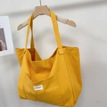 Close-up of yellow canvas tote bag featuring an external pocket and woven brand label - Osmanthus Yellow