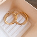 Detailed view of polished golden hoop earrings in a minimalist textured display tray - Diameter 4.5cm / Gold