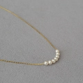 Elegant gold brass necklace with seven white round pearls on textured grey background - 7 White Pearls / Gold