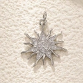 Silver starburst pendant with micro-pave cubic zirconia on a textured ivory surface - Silver Zircon Sun
