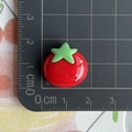 Vista macro di un ciondolo pomodoro in resina rossa con misura di 1,5 cm sul righello - Pomodoro
