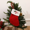 Knitted red Christmas stocking with white cuff featuring embroidered letter F and holly leaves - Letter F