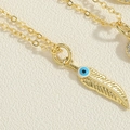 Detailed macro view of a gold feather pendant featuring a blue evil eye on white leather - Feather Eye